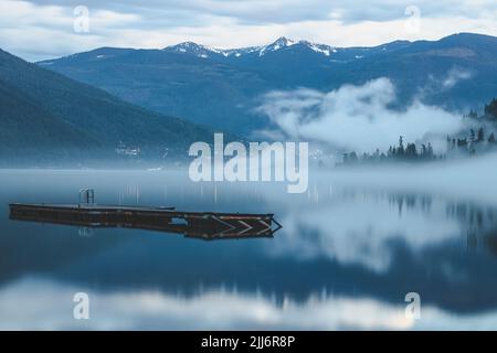 Moody, brouillard atmosphérique en soirée au-dessus du pittoresque lac Kootenay à Nelson, C.-B., Canada. Banque D'Images