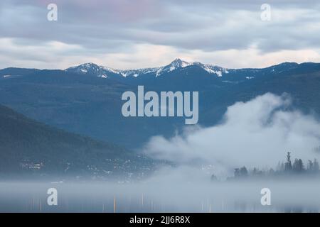 Moody, brouillard atmosphérique en soirée au-dessus du pittoresque lac Kootenay à Nelson, C.-B., Canada. Banque D'Images