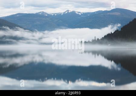 Moody, brouillard atmosphérique en soirée au-dessus du pittoresque lac Kootenay à Nelson, C.-B., Canada. Banque D'Images