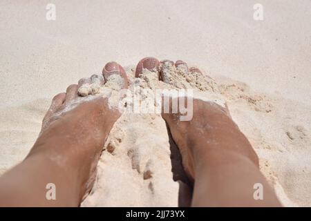 Pieds de dame dans le sable blanc chaud et doux sur la plage de la Barbade. Banque D'Images