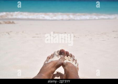 Pieds de dame dans le sable blanc chaud et doux sur la plage de la Barbade. Banque D'Images