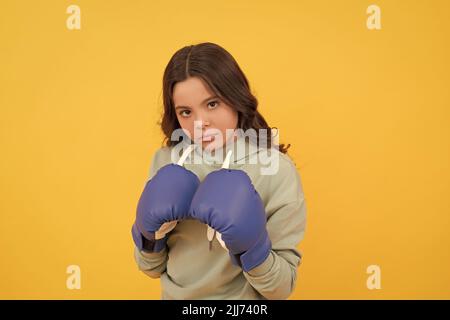 portrait d'enfant sérieux en gants de boxe sur fond jaune Banque D'Images