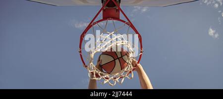 ballon de basket-ball punk à travers anneau de filet avec les mains, gagnant Banque D'Images