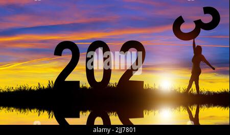 Silhouettes tenant le numéro 3 sur la colline tout en célébrant 2023 ans dans le lever du soleil arrière-plan. Joyeux Noël et Bonne Année. Banque D'Images