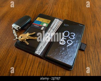 Lac Elsinore, CA, Etats-Unis - 23 juillet 2022 : porte-monnaie pour téléphone cellulaire avec cartes de crédit, espèces et clés de voiture. Banque D'Images