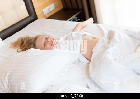 Rire dormir téléphone fille jeune mobile belle couverture de lit dormant, de la chambre caucasienne pour la santé et la bonne sieste, le coucher beauté. Faites face à un endroit confortable Banque D'Images