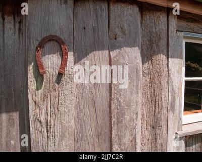 Vieux fer à cheval rouillé sur le mur extérieur d'un hangar en bois dans la campagne de la Nouvelle-Zélande. Banque D'Images
