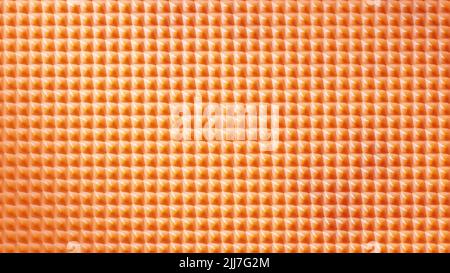 3D rendu. Gros plan sur la texture du filet orange. Motif de cellules en nid d'abeille orange. Texture plastique. Un fond heureux et positif se compose de plusieurs carrés. Texture orange avec petites formes pointues. Banque D'Images
