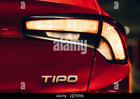 Magnifique tipo de fiat rouge garée dans un garage sombre avec des lumières avant et arrière éblouissantes. Banque D'Images