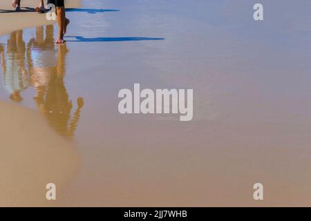 Réflexion dans l'eau des personnes marchant sur la plage méditerranéenne. Israël Banque D'Images