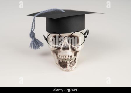 Crâne en plastique avec bonnet et lunettes universitaires. Banque D'Images