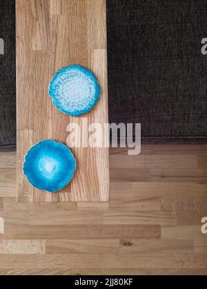 Table étroite en bois avec deux dessous de verre. Dessous de carafes en résine époxy à poser sur la table de l'ordinateur portable. Détails de l'intérieur du salon. Banque D'Images