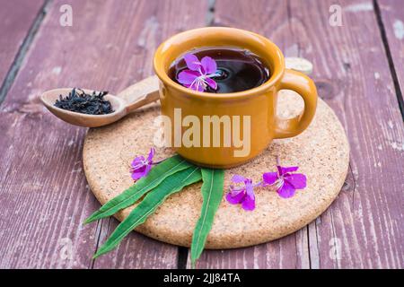 Thé Ivan ou chai. Tisane de fleurs d'herbes dans une tasse sur fond de bois. Thé traditionnel russe au kopor. Banque D'Images