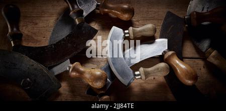 Vue de dessus de la collection de couteaux à l'ancienne mezzaluna avec des lames incurvées et des poignées en bois placées sur la table dans la cuisine Banque D'Images
