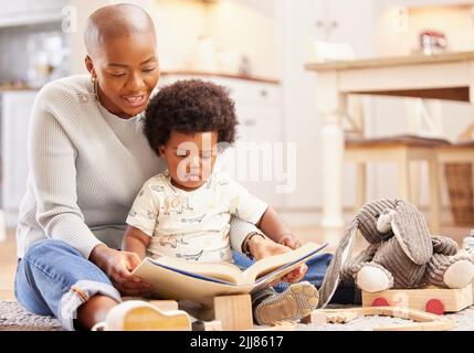 Entrez dans votre imagination avec un bon livre. Une jeune mère et fille jouant dans le salon à la maison. Banque D'Images