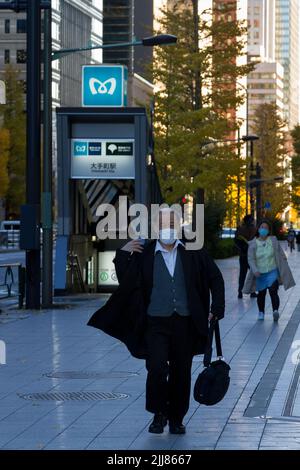 Un salaryman japonais, portant un masque chirurgical contre COVID19 infections marche dans la rue à Otemachi, Tokyo, Japon. Banque D'Images