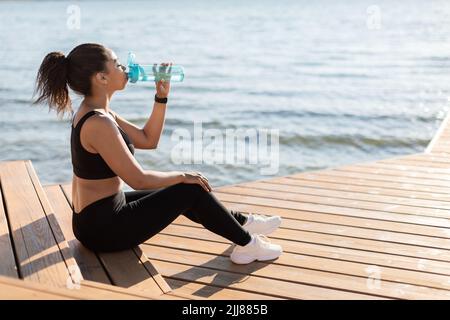 Femme afro-américaine sportive fatiguée qui boit de l'eau Banque D'Images