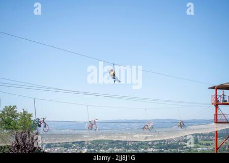 Bonne fille glisse ou escalade Zipline contre le ciel bleu Banque D'Images