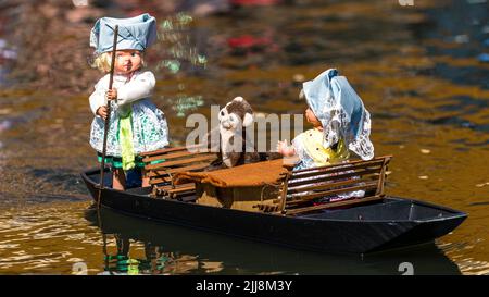 23 mars 2022, Brandebourg, Lübbenau : deux poupées en costumes traditionnels typiques de la forêt de Spree et une loutre voguant sur une barge modèle radiocommandée électrique sur la Spree à Lübbenau. Photo: Frank Hammerschmidt/dpa Banque D'Images