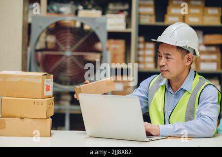 Ingénieur senior homme vérifiant le stock boîte de stockage à la recherche de la pièce de produits pour l'expédition. Banque D'Images