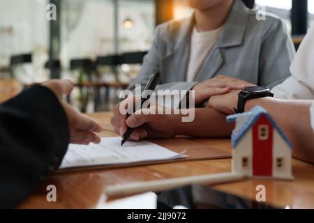 Un jeune couple heureux reçoit une merveilleuse affaire après avoir signé un contrat pour acheter une maison. Le courtier et le client se bousculer après avoir fait une bonne affaire Banque D'Images