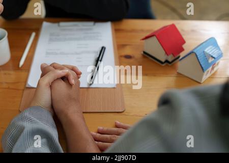 Un jeune couple heureux reçoit une merveilleuse affaire après avoir signé un contrat pour acheter une maison. Le courtier et le client se bousculer après avoir fait une bonne affaire Banque D'Images