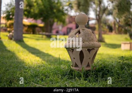 lanterne de poterie en céramique d'argile assise sur l'herbe dans un jardin pendant le coucher du soleil Banque D'Images