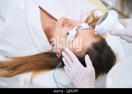 La cosmétologue féminine effectue une procédure de photoréjuvenation du front Banque D'Images