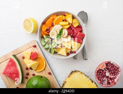 Bol de salade de fruits frais sur fond blanc, vue du dessus Banque D'Images
