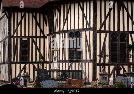 Des fenêtres en bois sculptées surmontées d'arches en fer à cheval éclairaient le choeur polygonal de l'église Saint-Nicolas, l'église du village restaurée datant des 16th et 17th siècles d'Outines, dans le pays du Der de la Marne, au Grand-est, en France. Le bâtiment est le plus grand et le plus monumental de toutes les églises historiques à colombages ou à pans de bois de la région de Champagne, avec d'énormes piliers et poutres en chêne soutenant son toit rouge recarrelé et des bardeaux en bois qui lui ajoutent sa spire mince. Banque D'Images