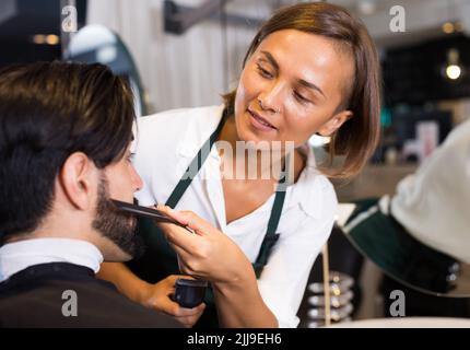 femme coiffeur rasage barbe de l'homme dans un salon de coiffure Banque D'Images