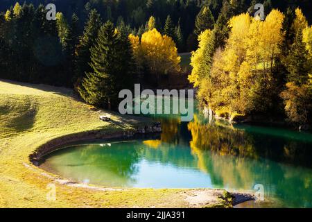 Vue d'automne ensoleillée sur le lac de Soraga dans le village de Soraga di Fassa, province de trente, Italie, Alpes Dolomites. Photographie de paysage Banque D'Images