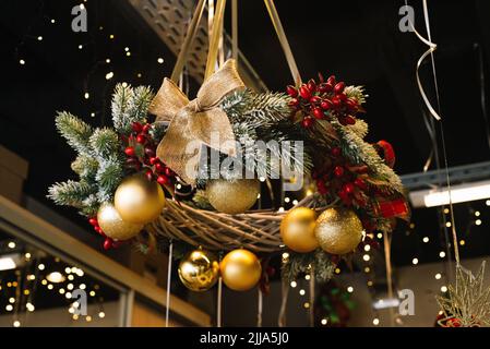 Décorations de Noël, branche de pin attachée dans une couronne, ornée de ballons, d'arcs, de neige artificielle et de baies Banque D'Images