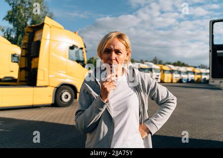 Femme originaire du Caucase d'âge moyen travaillant comme conducteur de camion. Fumer sur un parking de camions Banque D'Images