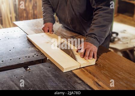 carpenter scie une planche en bois avec une machine à charpenterie. ancienne boutique de menuiserie rustique. Travail sur une machine à bois Banque D'Images