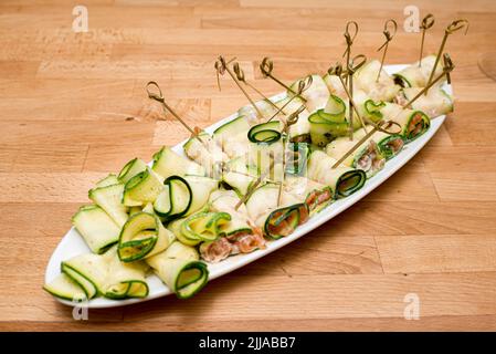 Rouleaux de courgettes avec garniture au fromage cottage. Beaucoup de portions de rouleaux brodés sur une longue assiette. Banque D'Images