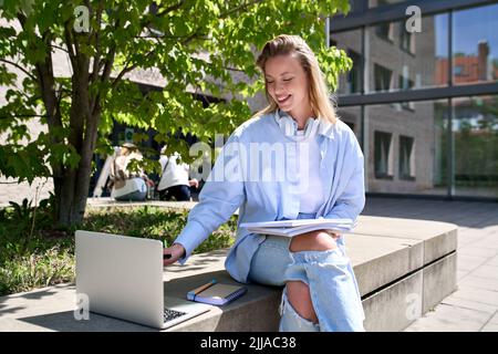 Jeune fille souriante étudiant en utilisant un ordinateur portable étudiant à l'extérieur dans le campus universitaire. Banque D'Images