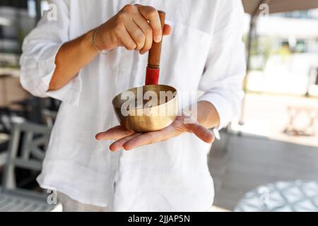 Les mains de l'homme court utilisant le bol de chant dans la thérapie de guérison sonore à l'extérieur, gros plan. Banque D'Images