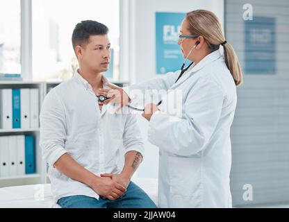 C'est une cause de préoccupation. Un médecin examinant un patient avec un stéthoscope lors d'une consultation dans une clinique. Banque D'Images