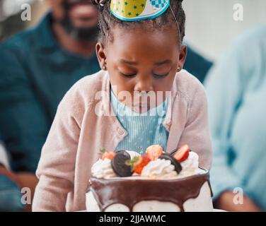 Shes le centre de l'amour et toute l'attention aujourd'hui. Une adorable petite fille soufflant des bougies pendant sa fête d'anniversaire. Banque D'Images