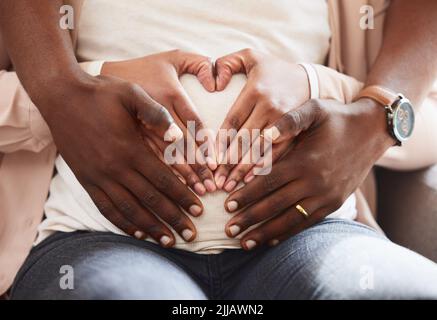 Des mains pleines d'amour. Un couple affectueux et méconnaissable de parents assis sur le canapé à la maison. Banque D'Images