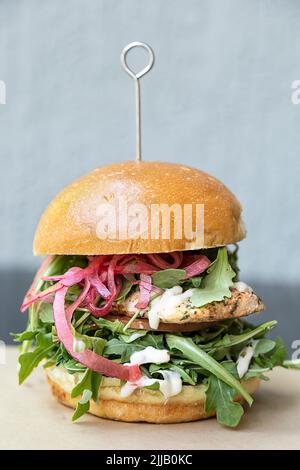 Hamburger de saumon grillé au fromage, à la tomate, à l'arugula et aux oignons Banque D'Images