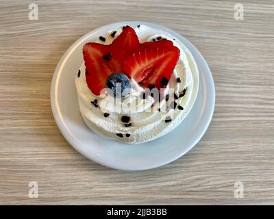 Pavlova, dessert à base de meringue, crème fouettée et chocolat, tranches de fraises et décoration aux myrtilles. Le gâteau porte le nom de la ballerine russe Banque D'Images