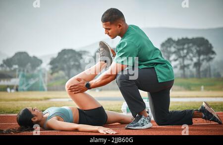 Vous ne pouvez pas courir avec cette blessure. Un paramédical sportif fournissant les premiers soins à un athlète sur une piste de course. Banque D'Images