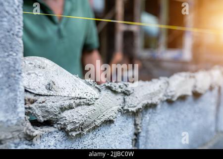 Les travailleurs utilisent des truelles pour construire des murs ou des murs avec des briques et du mortier. Banque D'Images