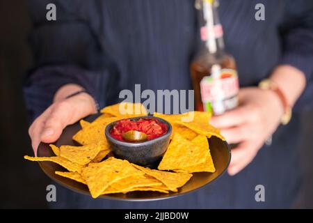 Assiette pour les mains des femmes avec plat mexicain, sauce au piment rouge nachos et bouteille de bière. Style de vie cuisine de rue. Banque D'Images