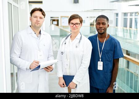 Portrait à la taille de divers groupes de médecins regardant la caméra dans l'intérieur moderne de l'hôpital Banque D'Images