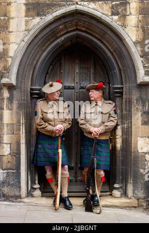 Le festival de Lincoln des années 1940 s'est tenu dans le quartier de la ville de Hailgate, dans le haut de la colline, près du château et de la cathédrale. Deux hommes vêtus de façon identique en costume d'époque posent dans une porte d'église à Bailgate. Banque D'Images