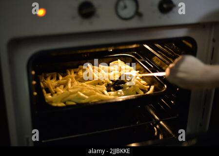 Personne cuisant des pommes de terre dans un four Banque D'Images
