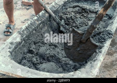 Les ouvriers remuent ou mélangent le ciment avec des pelles sur le chantier. Banque D'Images